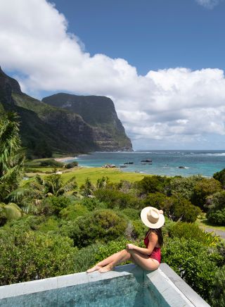 一位女士在豪勳爵島（Lord Howe Island）卡佩拉旅館的泳池邊欣賞美景
